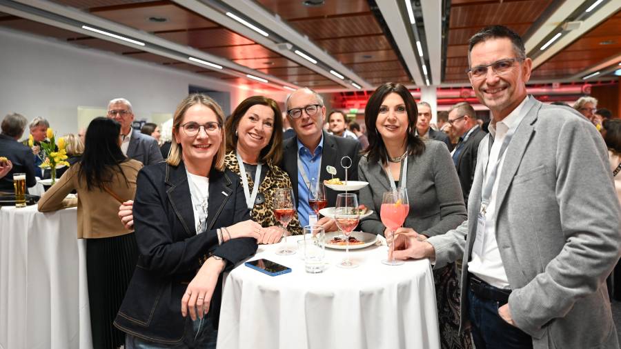 Sechs Personen stehen lachend um einen Stehtisch beim CDN 2025