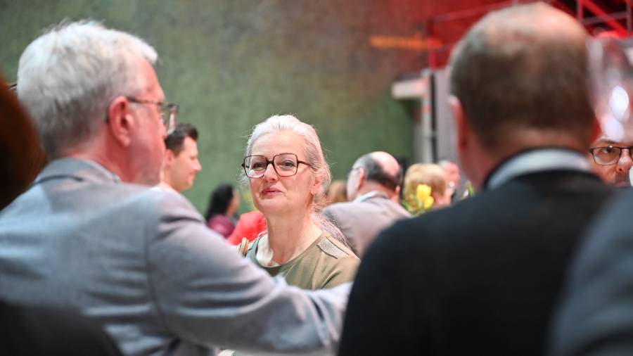 Frau mit grauen Haaren spricht an einem Tisch, Fokus auf ihr Gesicht
