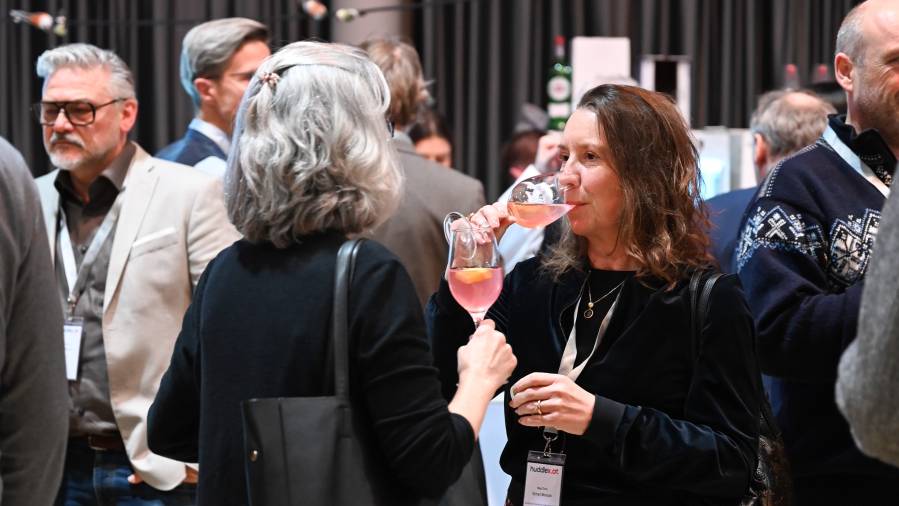 Zwei Frauen stoßen mit roséfarbenen Getränken bei einem Event an