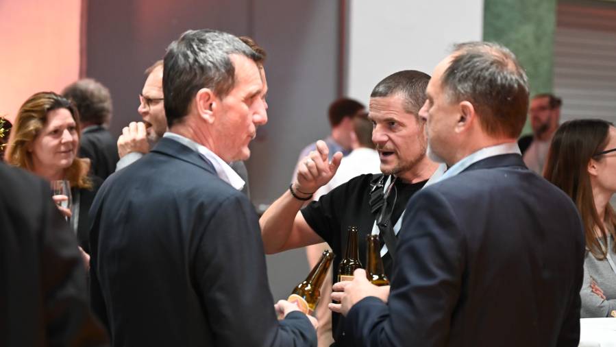 Drei Männer im Gespräch mit Bierflaschen in der Hand beim CDN 2025